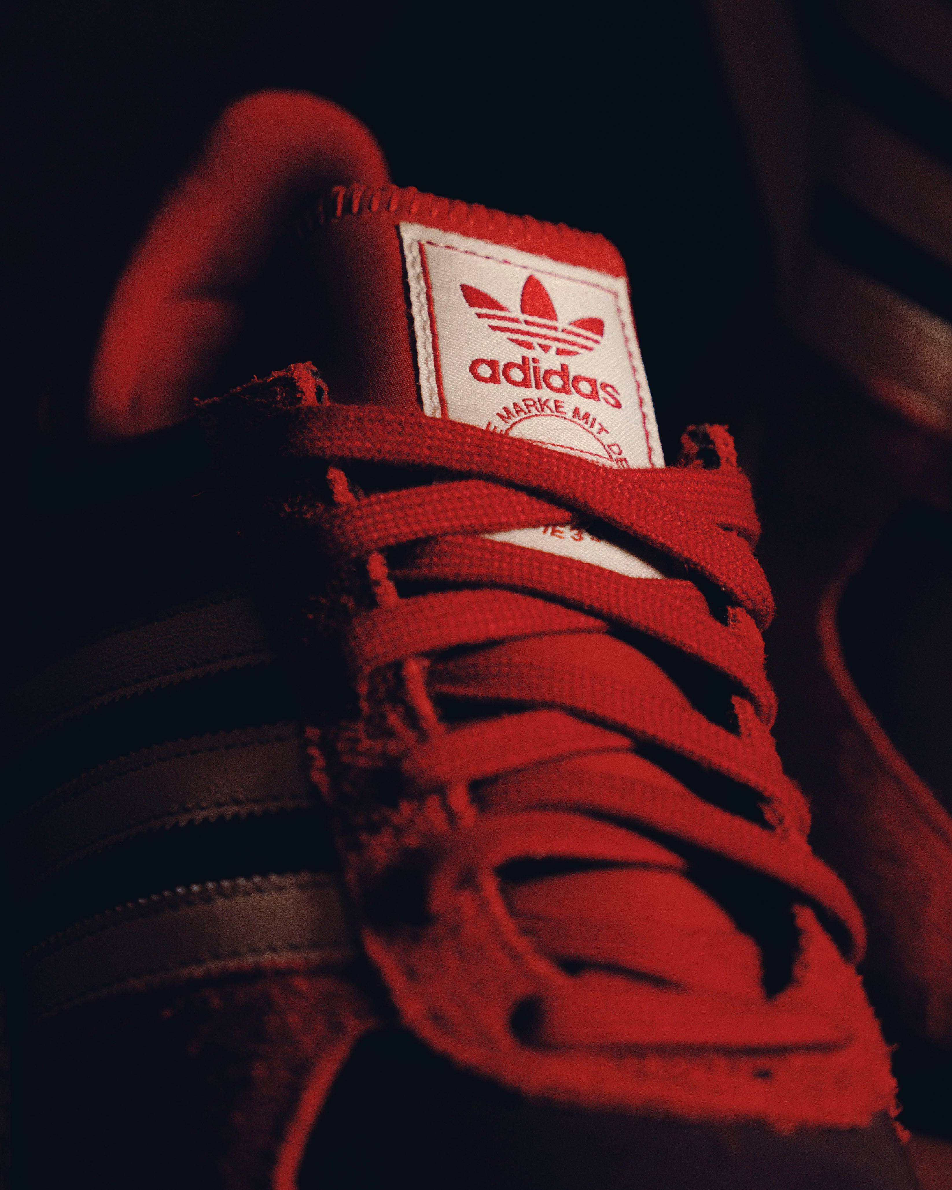 Close-up of red Adidas sneaker with white label and signature three stripes