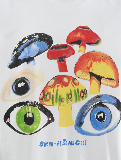 White graphic tee with colorful mushrooms, illustrated eyes, and 'Bueno - it Means Good' text.