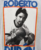 Graphic t-shirt featuring a pixelated boxer image and bold blue text on heather gray fabric.