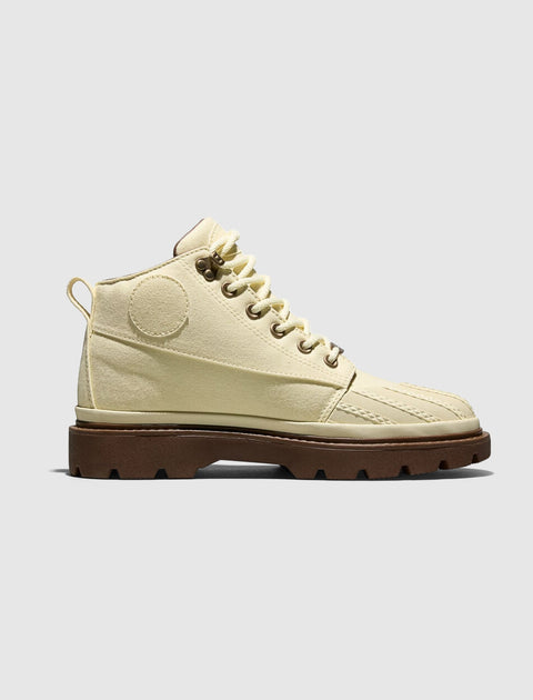 Cream high-top canvas boot with brown lug sole, side view on white background