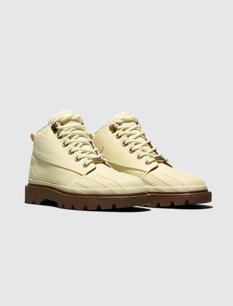 Beige lace-up boots with rugged brown soles on plain background