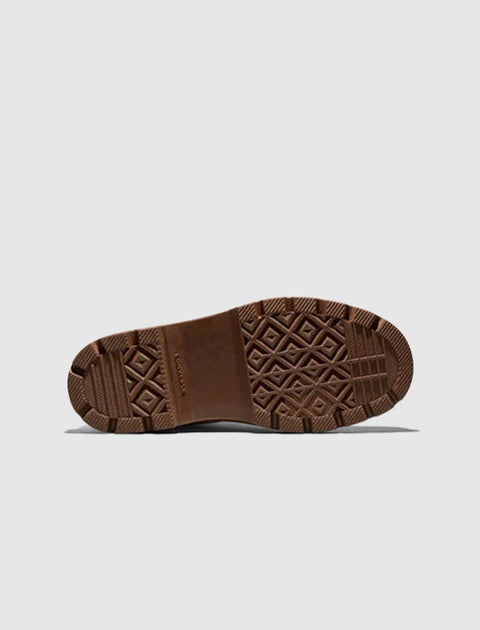 Brown rubber boot outsole with grippy tread pattern on a light background