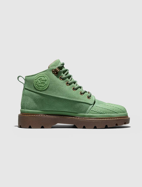 Green suede lace-up boot with embossed side logo and brown lug sole on white background