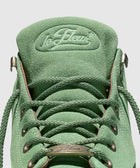 Close-up of green suede sneaker with braided laces and la fleur logo on the tongue