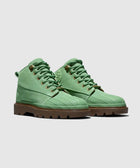 Green suede lace-up boots with rugged brown soles on a plain background