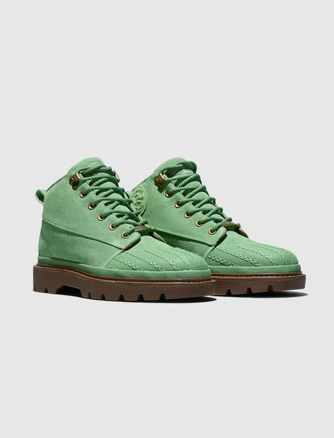 Green suede lace-up boots with rugged brown soles on a plain background
