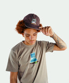 Man in streetwear graphic tee and embroidered black cap, minimal white background