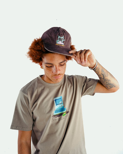 Man in streetwear graphic tee and embroidered black cap, minimal white background