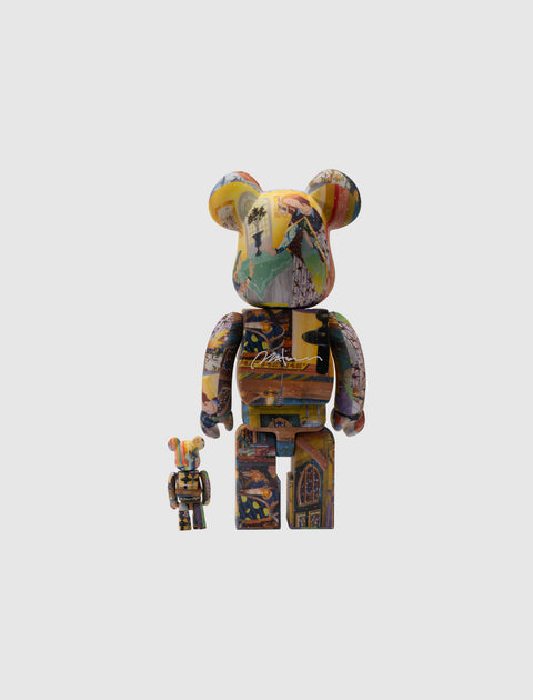 Two Bearbrick art collectible figures with colorful graphic designs on a plain background