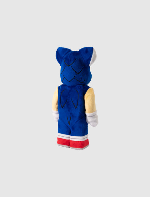 Blue and beige plush toy with red shoes and pointed ears, viewed from the back