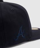 Close-up of a navy blue baseball cap with embroidered A logo on the side