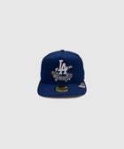Blue fitted baseball cap with LA logo and cartoon skateboard graphic, streetwear style.