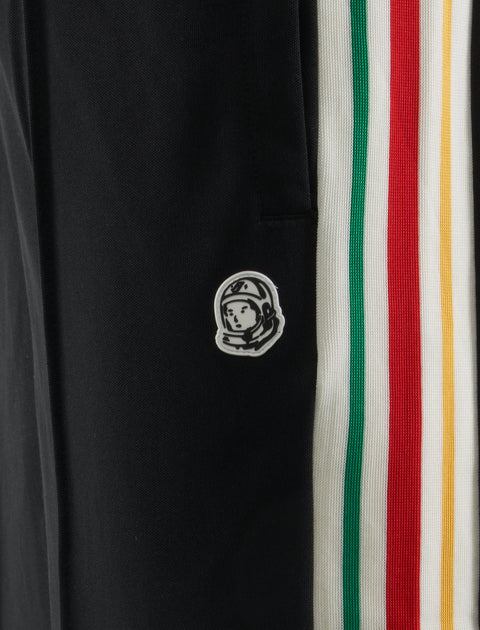 Black athletic pants with astronaut patch and green, red, yellow striped side panel