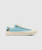 Light blue low-top sneaker with white sole, cream laces, and cartoon dog detail on heel