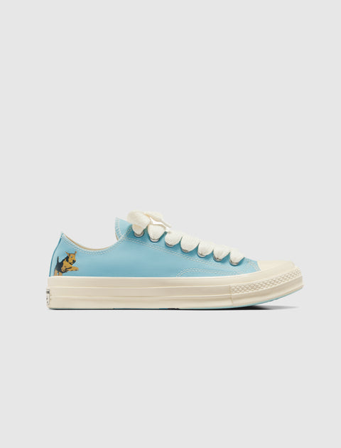 Light blue low-top sneaker with white sole, cream laces, and cartoon dog detail on heel