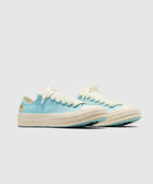 Light blue low-top sneakers with off-white laces and sole, cartoon graphic on heel