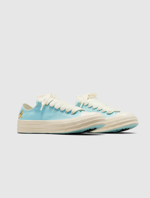 Light blue low-top sneakers with off-white laces and sole, cartoon graphic on heel