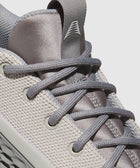 Close-up of grey mesh sneaker with textured laces and knit upper, modern streetwear shoe