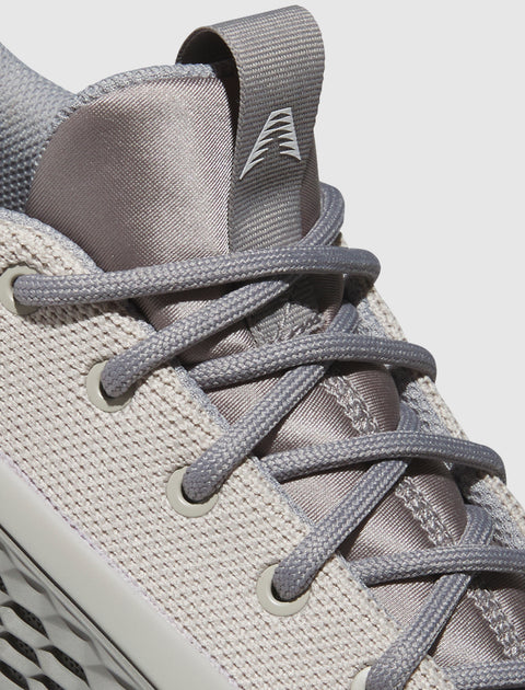 Close-up of grey mesh sneaker with textured laces and knit upper, modern streetwear shoe