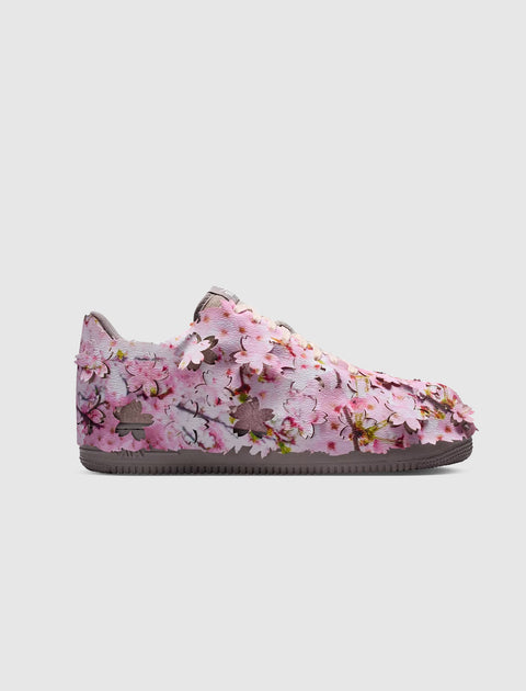 Pink floral low-top sneaker with cherry blossom details on a white background