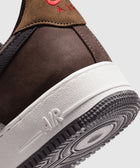 Close-up of brown and black sneaker heel with red embroidery and white textured sole