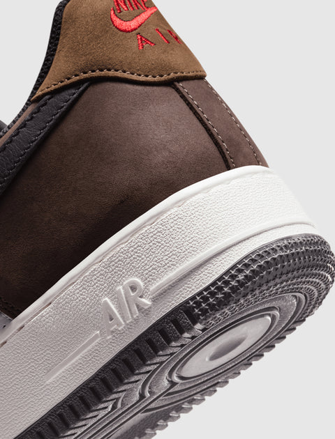 Close-up of brown and black sneaker heel with red embroidery and white textured sole
