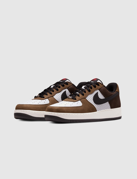 Brown and white low-top sneakers with black accents and perforated side panels on a light background.