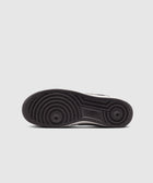 Black rubber outsole of a men's sneaker with circular tread pattern on a gray background