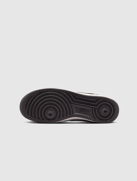 Black rubber outsole of a men's sneaker with circular tread pattern on a gray background