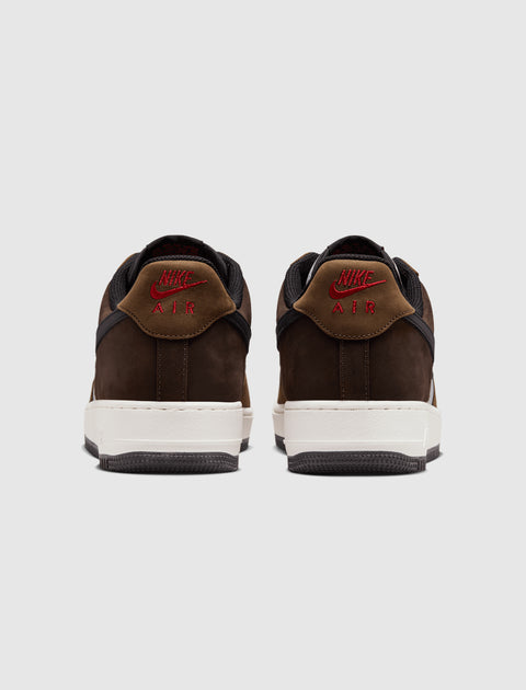 Rear view of brown Nike Air Force 1 Low sneakers with red logo and white sole on gray background