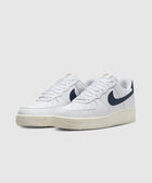 White low-top sneakers with navy swoosh logo and cream sole on light background