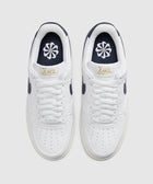 White low-top sneakers with navy accents and flower logo on insoles, viewed from above