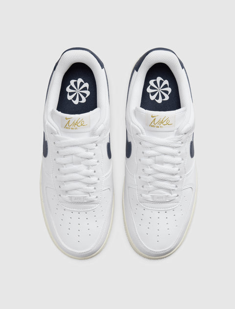 White low-top sneakers with navy accents and flower logo on insoles, viewed from above