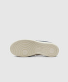Bottom sole of a white sneaker with circular grip pattern on a plain background
