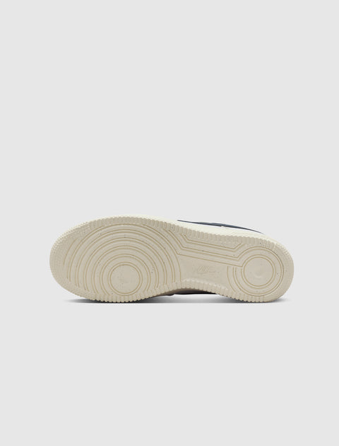 Bottom sole of a white sneaker with circular grip pattern on a plain background
