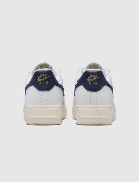 Back view of white Nike Air sneakers with navy and gold accents, men's streetwear shoes