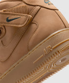 Close-up of tan suede mid-top sneaker with Velcro strap, Nike Swoosh logo, and AIR sole detail