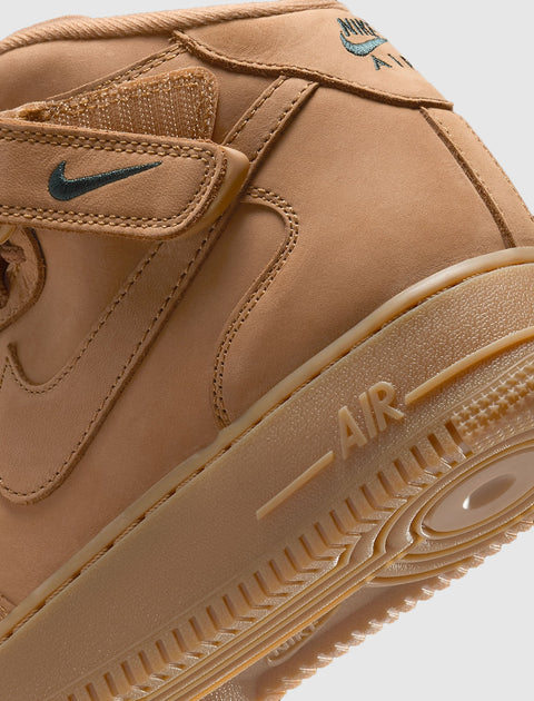 Close-up of tan suede mid-top sneaker with Velcro strap, Nike Swoosh logo, and AIR sole detail