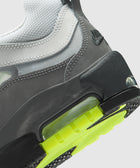 Close-up of a grey and white sneaker with neon green sole and visible air cushioning