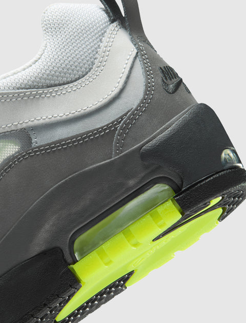 Close-up of a grey and white sneaker with neon green sole and visible air cushioning