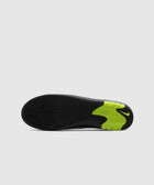 Black sneaker sole with textured grip and neon green Nike detail on white background