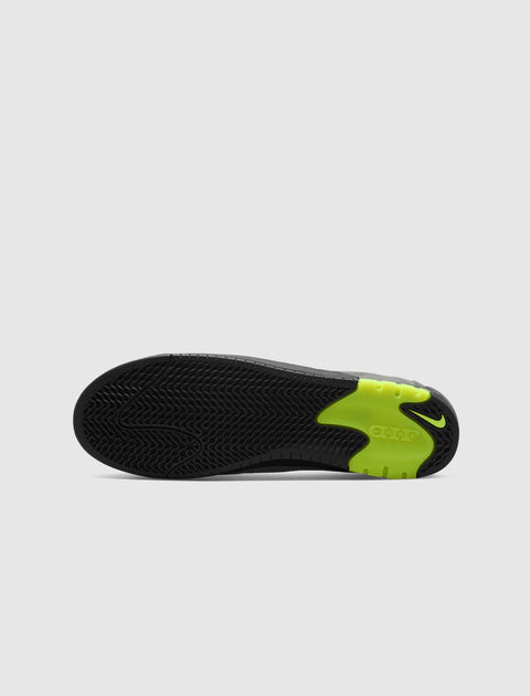 Black sneaker sole with textured grip and neon green Nike detail on white background
