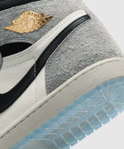 Close-up of a grey and white high-top sneaker with gold logo and icy blue sole