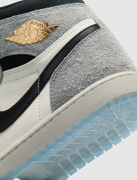Close-up of a grey and white high-top sneaker with gold logo and icy blue sole