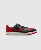 Black and red low-top sneaker with white sole, side view on plain background