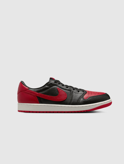 Black and red low-top sneaker with white sole, side view on plain background