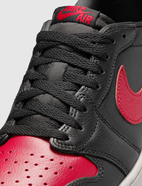 Black and red low-top sneaker with red Nike swoosh and perforated leather toe box