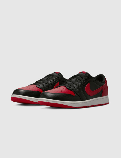 Black and red low-top sneakers with white midsoles, side view on plain background