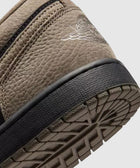 Close-up of brown and black sneaker heel with textured sole and stitched logo