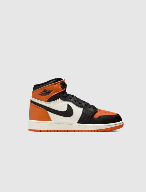 High-top sneaker with black, orange, and white color blocking on a light background
